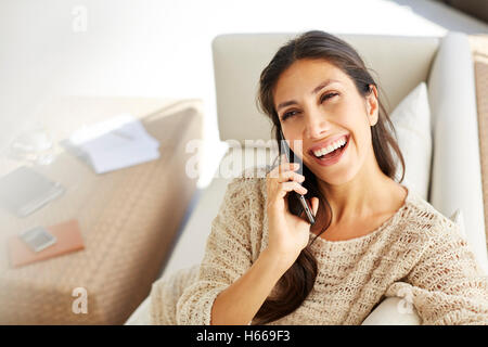 Laughing woman talking on cell phone on sofa Stock Photo