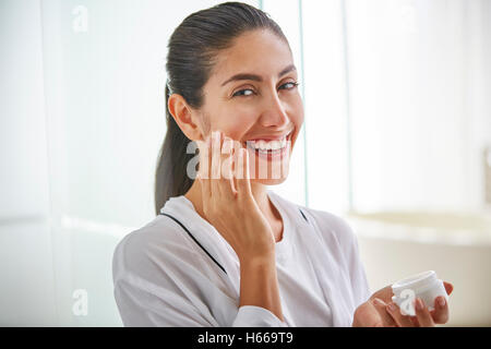 Portrait smiling woman apply face cream to cheek Stock Photo