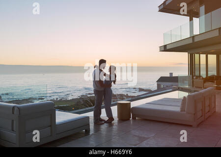 Affectionate couple hugging on luxury patio with ocean view Stock Photo