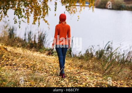 Lonely woman walking away in the autumn park Stock Photo