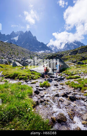 Hikers crossing a stream on the Grand Balcon Nord, Chamonix Valley, French Alps, France. Stock Photo