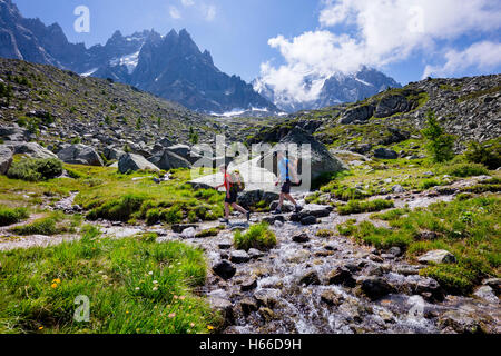 Hikers crossing a stream on the Grand Balcon Nord, Chamonix Valley, French Alps, France. Stock Photo