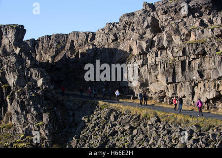 Toursits visting the rift valley in the Pingvellir national Park home of the ancient Icelandic parliement in Iceland, walking through the gorge and taking in the sites. Stock Photo