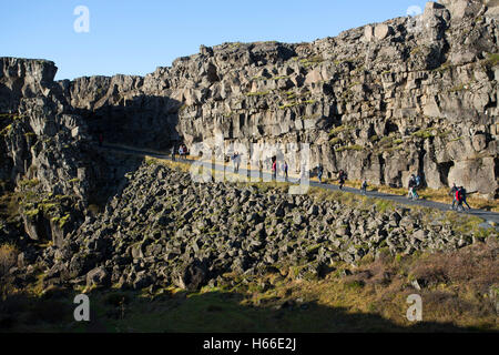 Toursits visting the rift valley in the Pingvellir national Park home of the ancient Icelandic parliement in Iceland, walking through the gorge and taking in the sites. Stock Photo