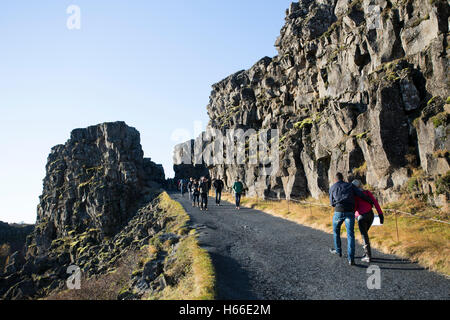 Toursits visting the rift valley in the Pingvellir national Park home of the ancient Icelandic parliement in Iceland, walking through the gorge and taking in the sites. Stock Photo
