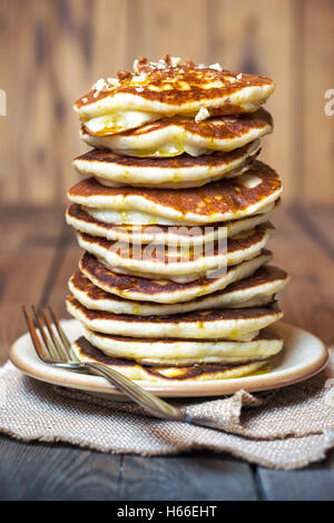 High stack of pancakes with syrup and walnuts on top. The rustic style. Shallow DOF Stock Photo