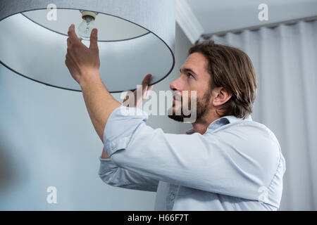 Man installing a bulb in living room Stock Photo
