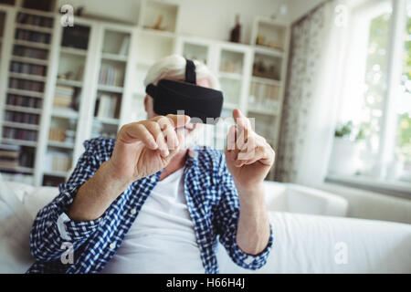 Senior man wearing virtual reality headset in living room Stock Photo