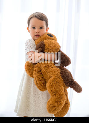 Cute little happy girl hugging big brown teddy bear Stock Photo