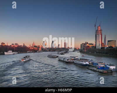 Wide view of North and South Bank with City of London Saint Paul's & The Shard with pleasure boat cruising downstream on River Thames, viewed from Waterloo Bridge London UK at sunset
