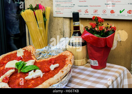 Pizza margherita, spaghetti and flask of Chianti red wine on a table outside a restaurant in Rome, Lazio, Italy Stock Photo