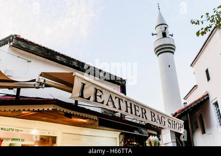 Leather handbag shop in Fethiye Market, Turkey, in the shadow of the local mosque minaret Stock Photo