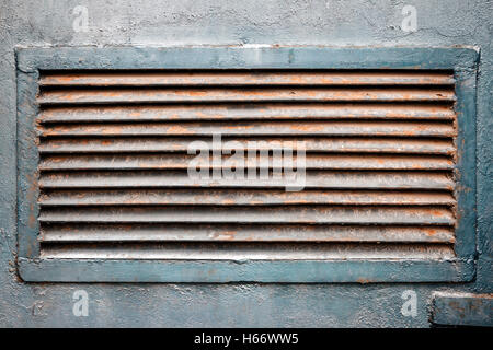 Rusty old ventilation grille on metal wall painted in blue Stock Photo