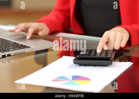 Closeup of a businesswoman hands accounting with a black calculator and a laptop sitting in a desktop at office Stock Photo