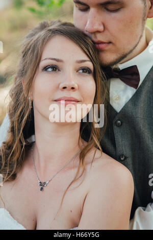 bride and groom standing arm in arm against the background grass and lakes. Stock Photo