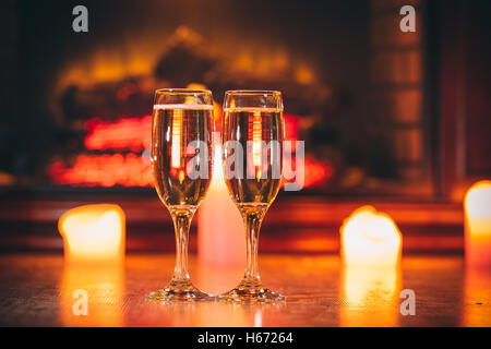 Beautiful Two glasses of champagne on blurred background with candles and a fireplace. The idea for postcards. Soft focus. Shall Stock Photo