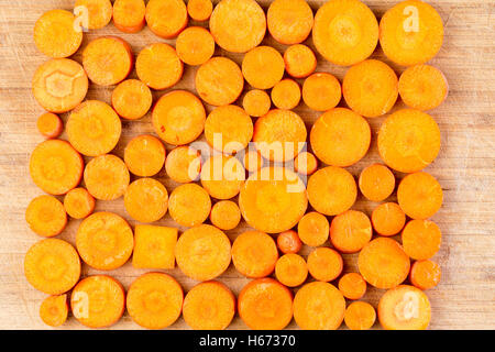 Top down view on chopped circular and rectangular orange colored carrots arranged in neat rows on cutting board Stock Photo