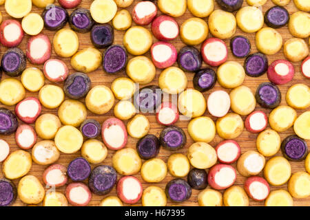 Sliced and topped mini baby potato background of fresh vegetables ready to be roasted in an overhead full frame view Stock Photo