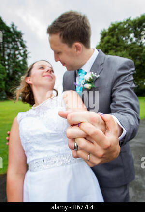 Bride and groom holding hands looking into each others eyes, taken with fisheye lens for added drama Stock Photo
