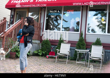 Woman talking on her cellphone outside on tailor shop patio. St Paul Minnesota MN USA Stock Photo