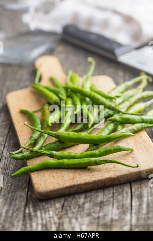 Green chili peppers on cutting board. Stock Photo