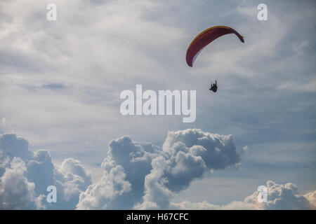 Color image of a paraglider flying, with clouds in the background. Stock Photo