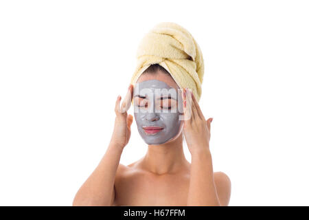 Woman with towel on her head and cosmetic mask on her face Stock Photo