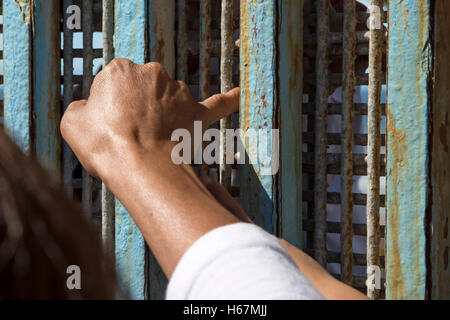 Tijuana, Mexico - Family members separated by deportation touch fingers through the U.S.-Mexico border fence. Stock Photo