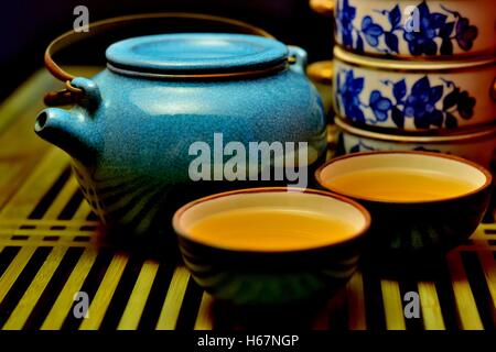 Chinese tea set with blue teapot, two teacups with Oolong tea and a blue and white porcelain food box on a bamboo tea tray Stock Photo