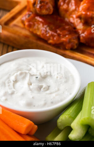 Blue cheese dressing for dipping served with celery sticks, carrot sticks and buffalo chicken wing with cayenne pepper  sauce Stock Photo
