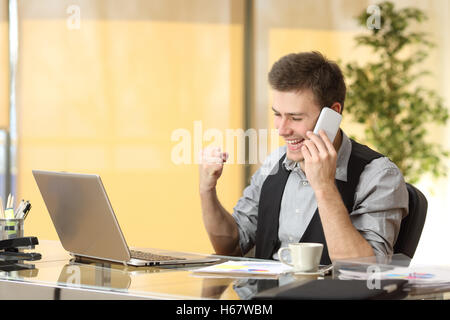 Excited businessman talking on the mobile phone while is watching business content in a laptop Stock Photo