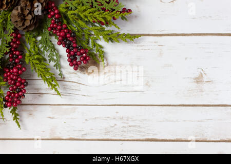 Christmas Garland with Pine Cones and Berries on a white wood plank board with room for writing or text in the background Stock Photo