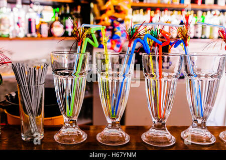 Multicoloured bendy straws in glasses on the counter of a bar, ready for cocktails. Stock Photo