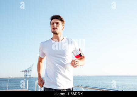Concentrated young handsome sportsman running on pier in the morning Stock Photo