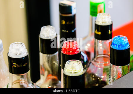 Multicoloured bottles on the counter of a bar with plastic flow restrictors/speed pourers to ensure accurate pouring by counting the number of seconds Stock Photo