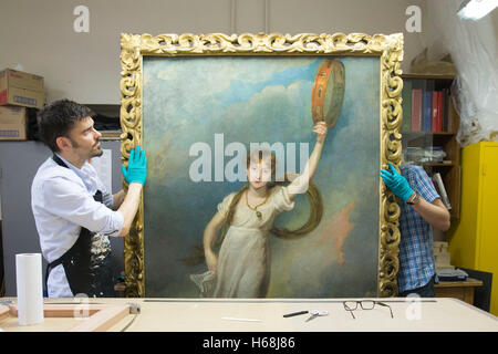 Conservators carry a newly reframed portrait of Horatia Nelson, the daughter of Emma Hamilton and naval hero Horatio Nelson, at the National Maritime Museum in London. Stock Photo