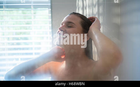 Woman taking a shower in bathroom Stock Photo