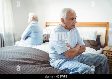 Sad senior couple sitting on bed Stock Photo