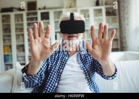 Senior man wearing virtual reality headset in living room Stock Photo