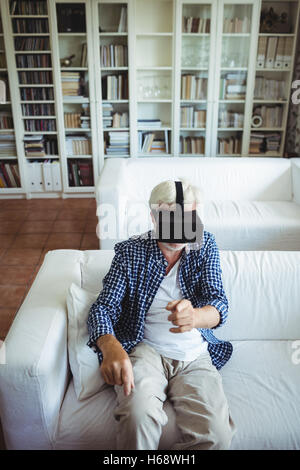 Senior man wearing virtual reality headset in living room Stock Photo