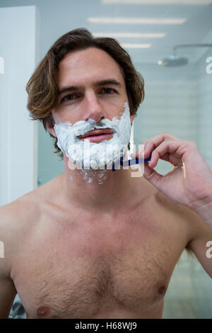 Man using a razor to shave his beard off Stock Photo