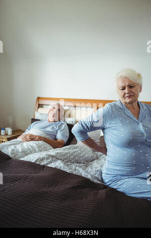 Senior woman suffering from backache sitting on bed Stock Photo