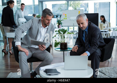 Businesspeople discussing over laptop Stock Photo