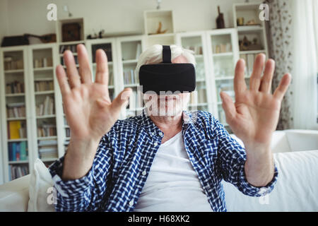 Senior man wearing virtual reality headset in living room Stock Photo