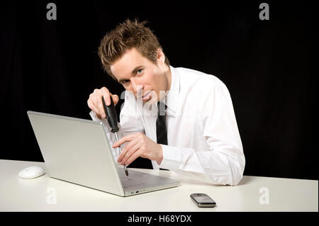 Businessman repairing a laptop with a screwdriver Stock Photo