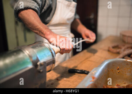 Man making sausages the traditional way using sausage filler. Stock Photo