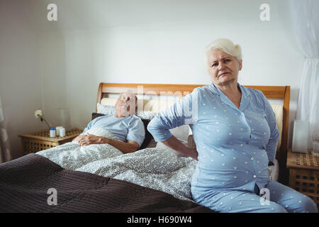 Senior woman suffering from backache sitting on bed Stock Photo