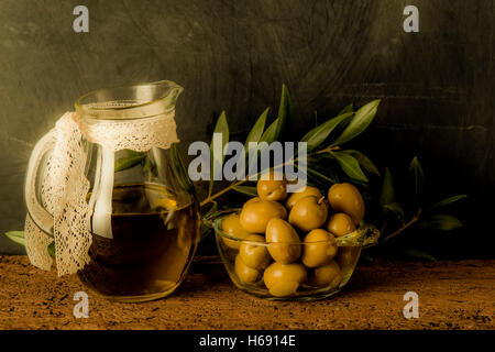 Olives and olive oil in glass jar on rustic background Stock Photo