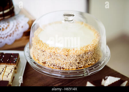 Carrot cake with nuts and glaze on glass cake stand. Stock Photo