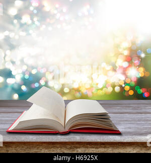 Open book on table in front of bright lights Stock Photo